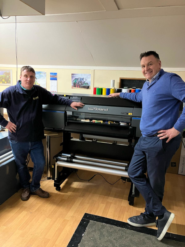 brian carry standing next to his new sign cutting machine